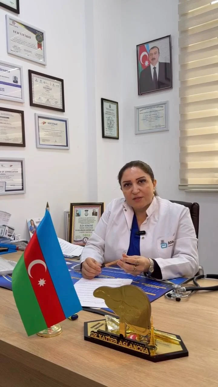 Dr. Xatirə Aslanova ağ xalatda, iş masasının arxasında
